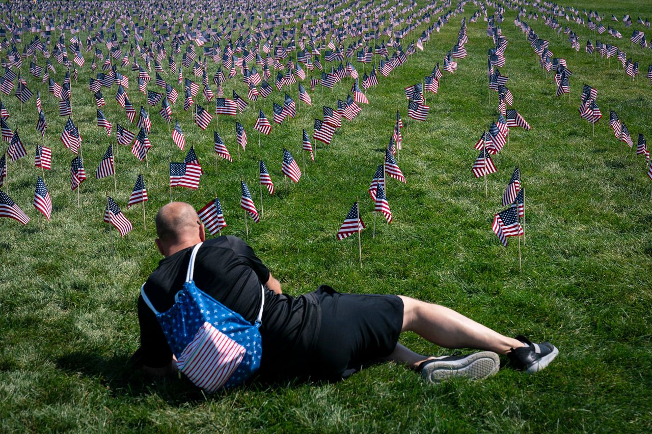 A man lays down to observe the<strong> </strong>2,977<strong> </strong>American flags placed on the National Mall in Washington, DC, representing the lives lost on 9/11, not including the hijackers.