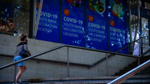 A woman walk past signage at a Covid-19 vaccination hub in Brisbane, Queensland, on August 17.