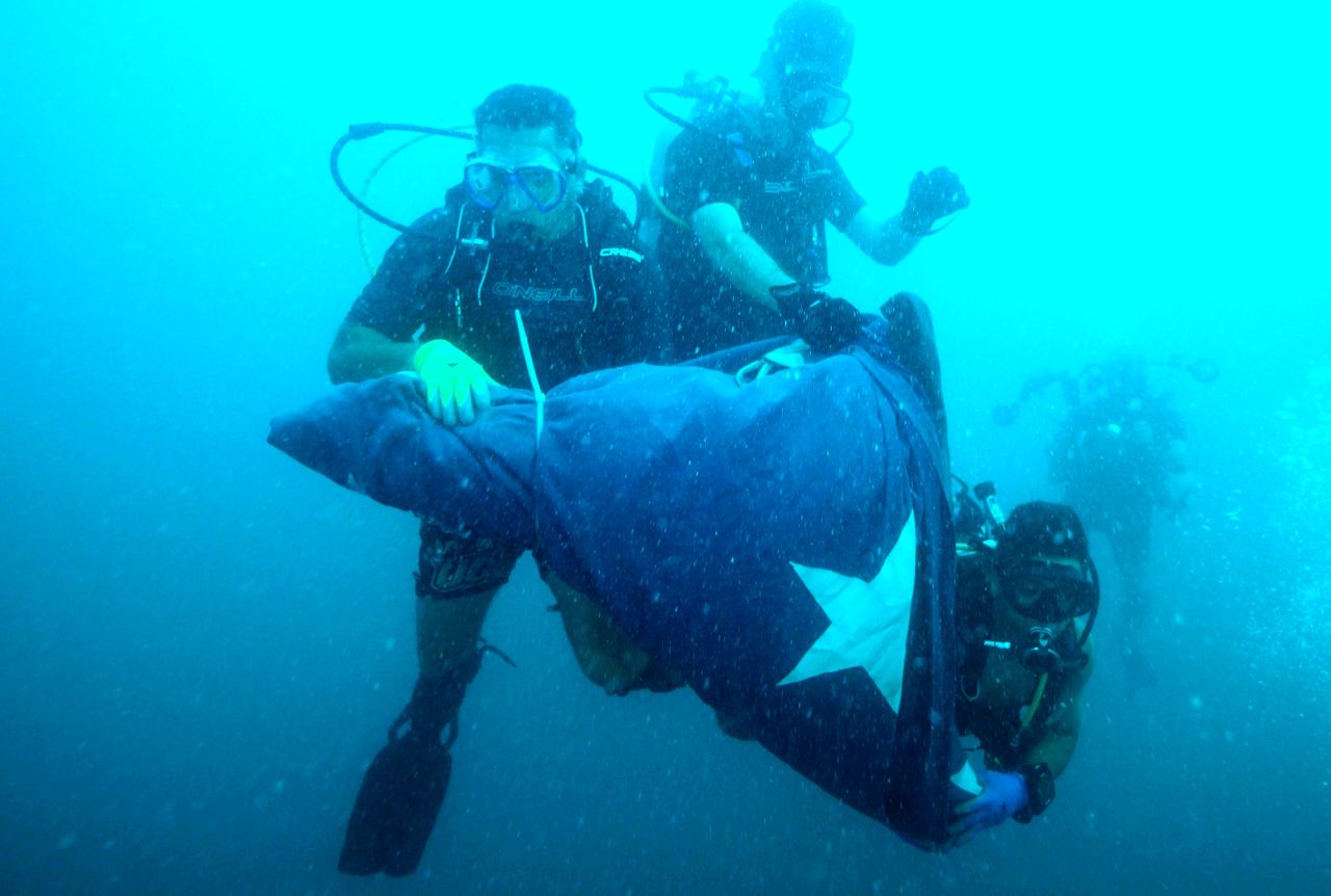 Divers carry a folded American flag underwater Saturday in the Florida Keys National Marine Sanctuary off Key West, Florida. The flag was unfurled on the Gen. Hoyt S. Vandenberg shipwreck in commemoration of 9/11. The Vandenberg, a 523-foot-long former Army troop transporter and Navy missile-tracking ship, was scuttled in 2009 as an artificial reef.