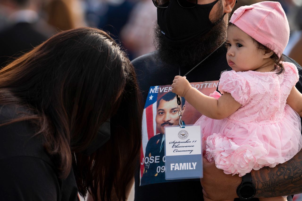 A baby holds a lanyard that reads "Family" during the ceremony at the Pentagon, indicating they are family members of a person who died on 9/11.
