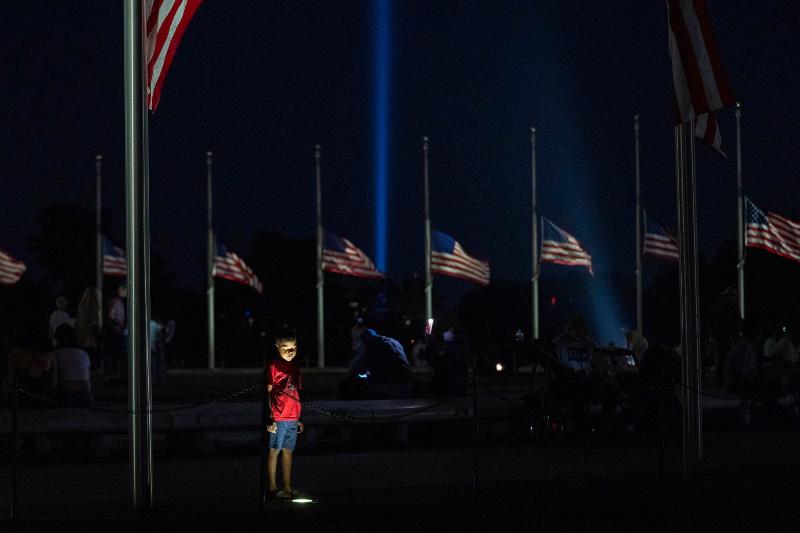 A child visits the Washington Monument as flags are flown at half-staff and a beam of light is cast into the sky from the Pentagon in honor of 9/11.