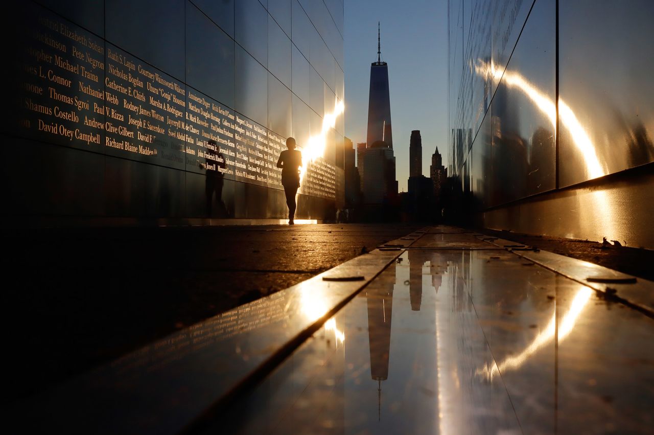 A person walks through the Empty Sky 9/11 memorial at Liberty State Park in Jersey City, New Jersey, as the sun rises Saturday behind lower Manhattan.