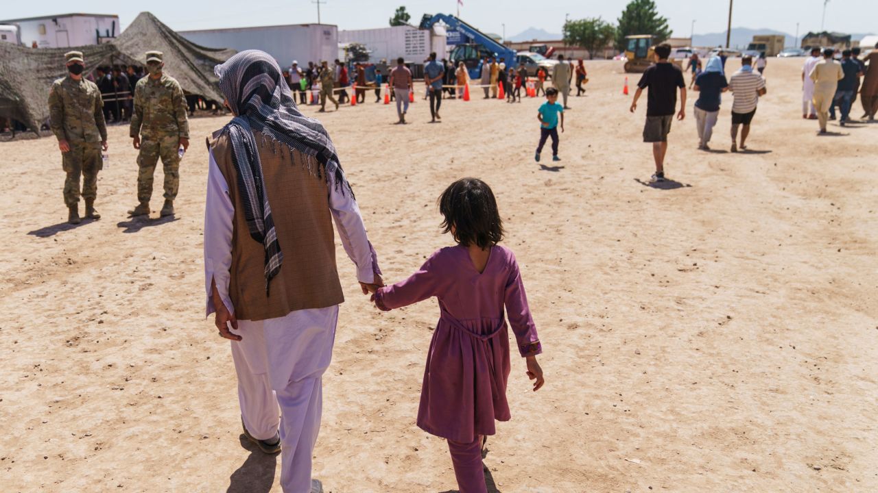 A man walks with a child through Fort Bliss' Doña Ana Village where Afghan refugees are being housed, in New Mexico, Friday, Sept. 10, 2021. 
