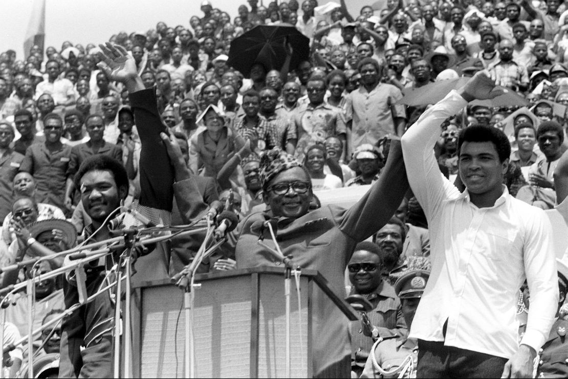 Zaire's President Mobutu Sese Seko (center) holds George Foreman (left) and Ali's arms aloft in Kinshaha on September 22, 1974 ahead of the fight dubbed "The Rumble in the Jungle."