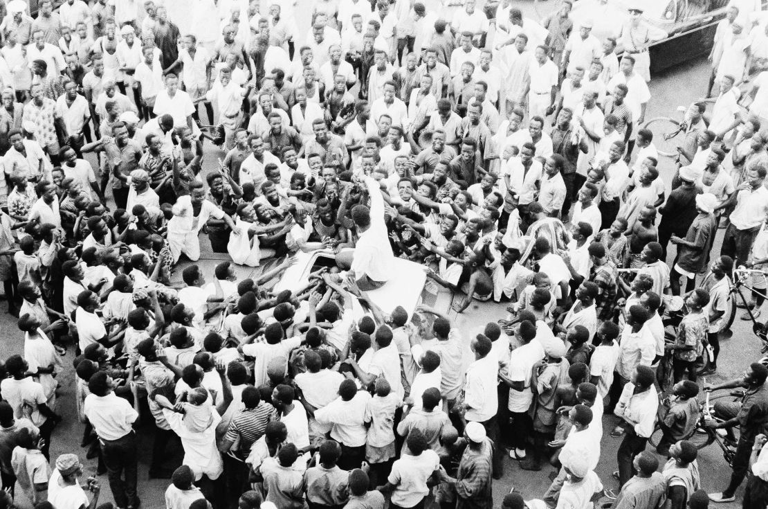 People swarm round world heavyweight boxing champion Muhammad Ali as he sits atop his car during the drive to his hotel after arriving at the airport in Lagos, Nigeria, on June 1, 1964.    