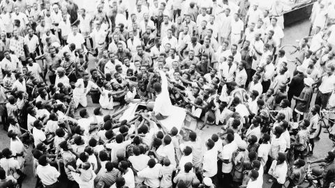 People swarm round world heavyweight boxing champion Muhammad Ali as he sits atop his car during the drive to his hotel after arriving at the airport in Lagos, Nigeria, on June 1, 1964.    