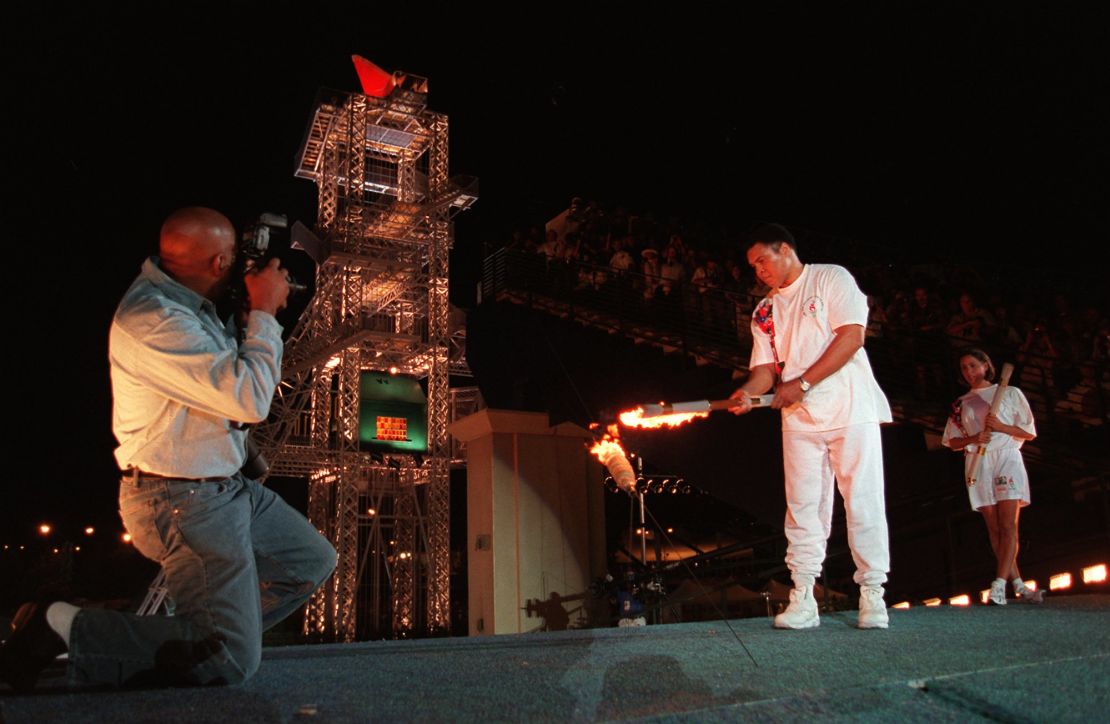 Muhammad Ali uses the Olympic torch to ignite the Olympic flame as swimmer Janet Evans, right, watches during the opening ceremony of the 1996 Summer Olympic Games in Atlanta, on July 19, 1996. 