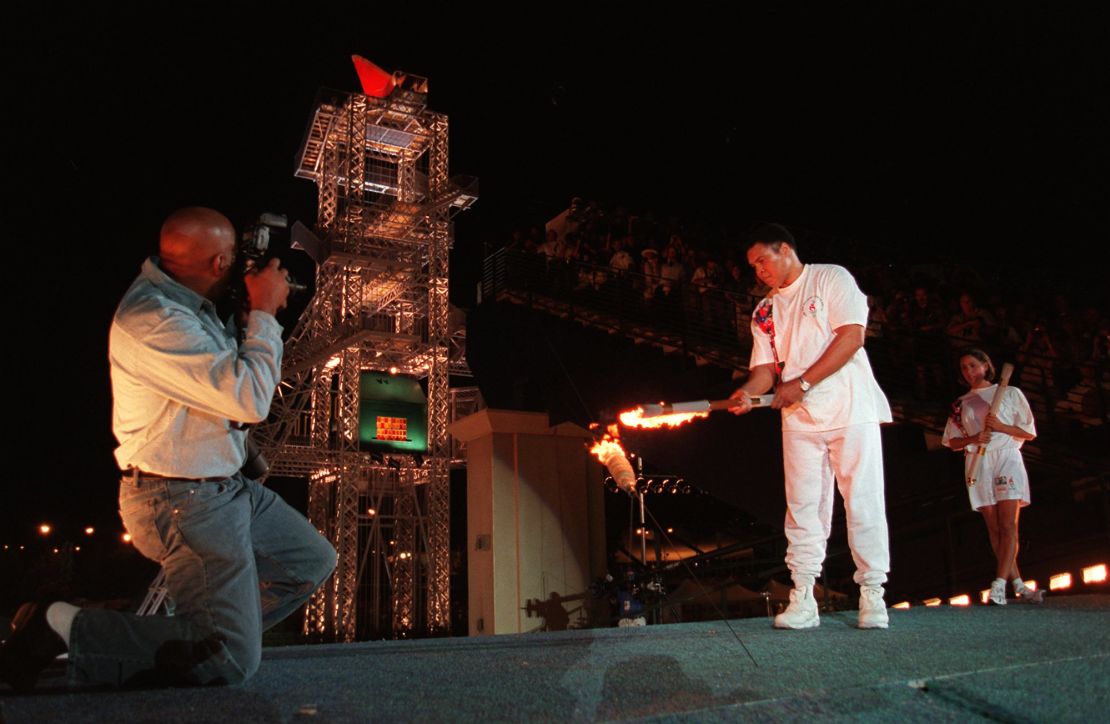 Muhammad Ali uses the Olympic torch to ignite the Olympic flame as Janet Evans, right, watches during the opening ceremony of the 1996 Summer Olympic Games in Atlanta, on July 19, 1996.