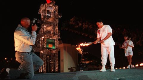 Muhammad Ali uses the Olympic torch to ignite the Olympic flame as Janet Evans, right, watches during the opening ceremony of the 1996 Summer Olympic Games in Atlanta, on July 19, 1996. 
