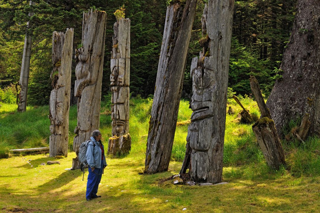 A visitor to Gwaii Haanas National Park in Haida Gwaii examines Haida mortuary poles.