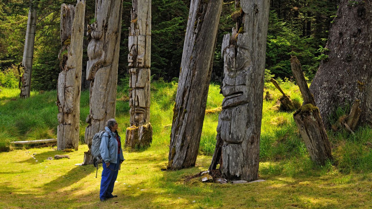 A visitor to Gwaii Haanas National Park in Haida Gwaii examines Haida mortuary poles.