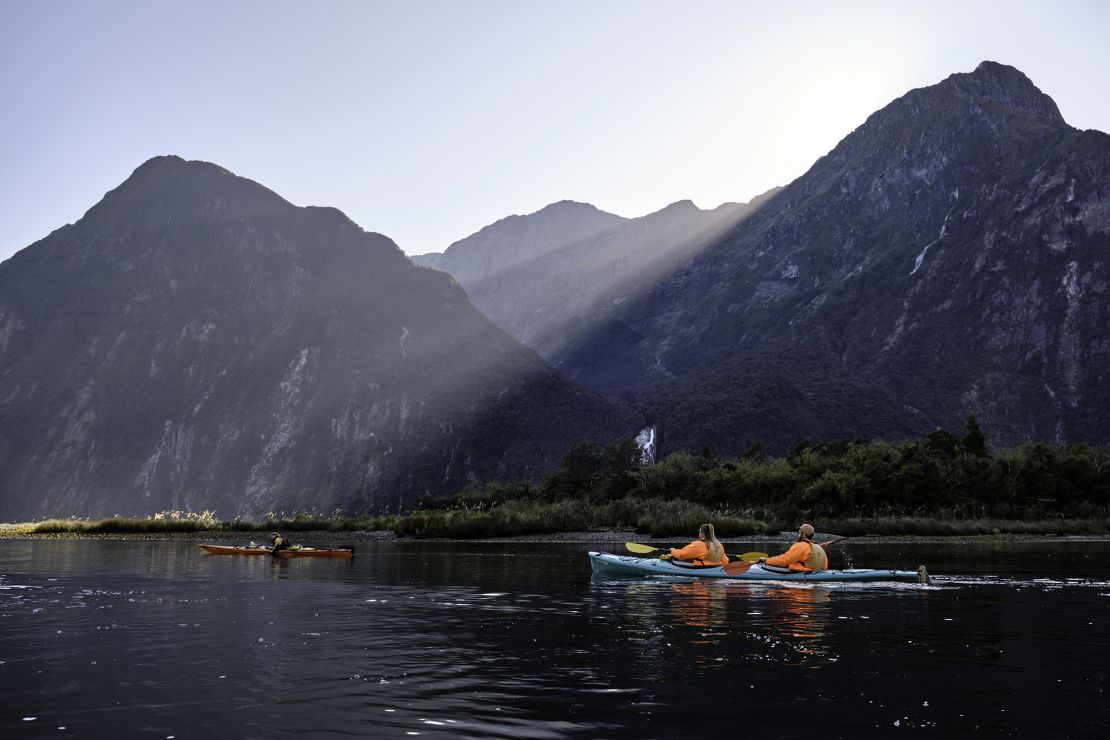 Tourists enjoing kayaking in the waters of the gorgeous Milford Sound. Before the pandemic, New Zealand came out the "Tiaki Promise."