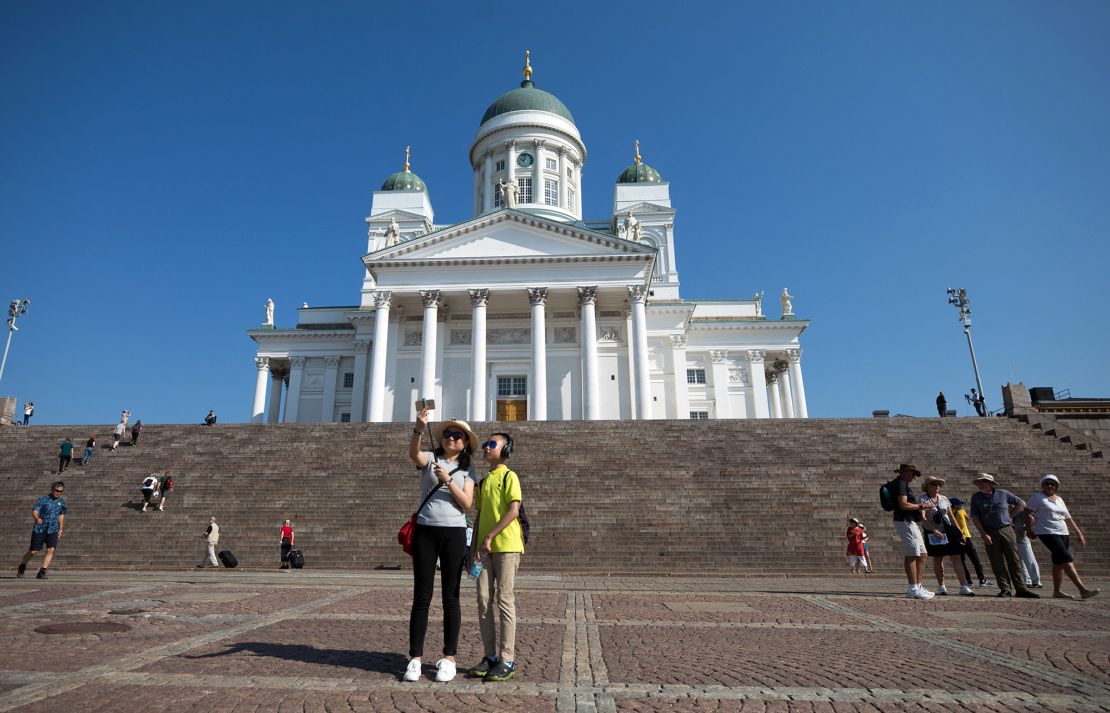 Tourists take a selfie photograph against the backdrop of the Helsinki Cathedral in Finland, which is using humor and rhymes to get its points across to visitors.