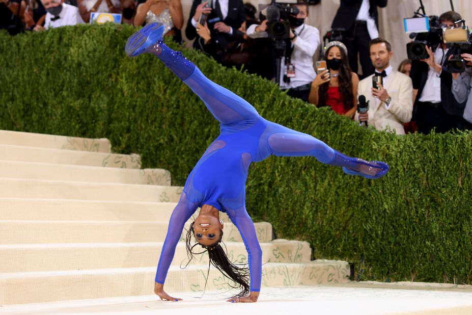 Gymnast Nia Dennis made a dramatic entrance wearing a blue Stella McCartney dress, which featured a sheer mesh skirt. As she approached the steps, she removed her skirt to reveal a crystal-embellished blue bodysuit and launched into acrobatics.