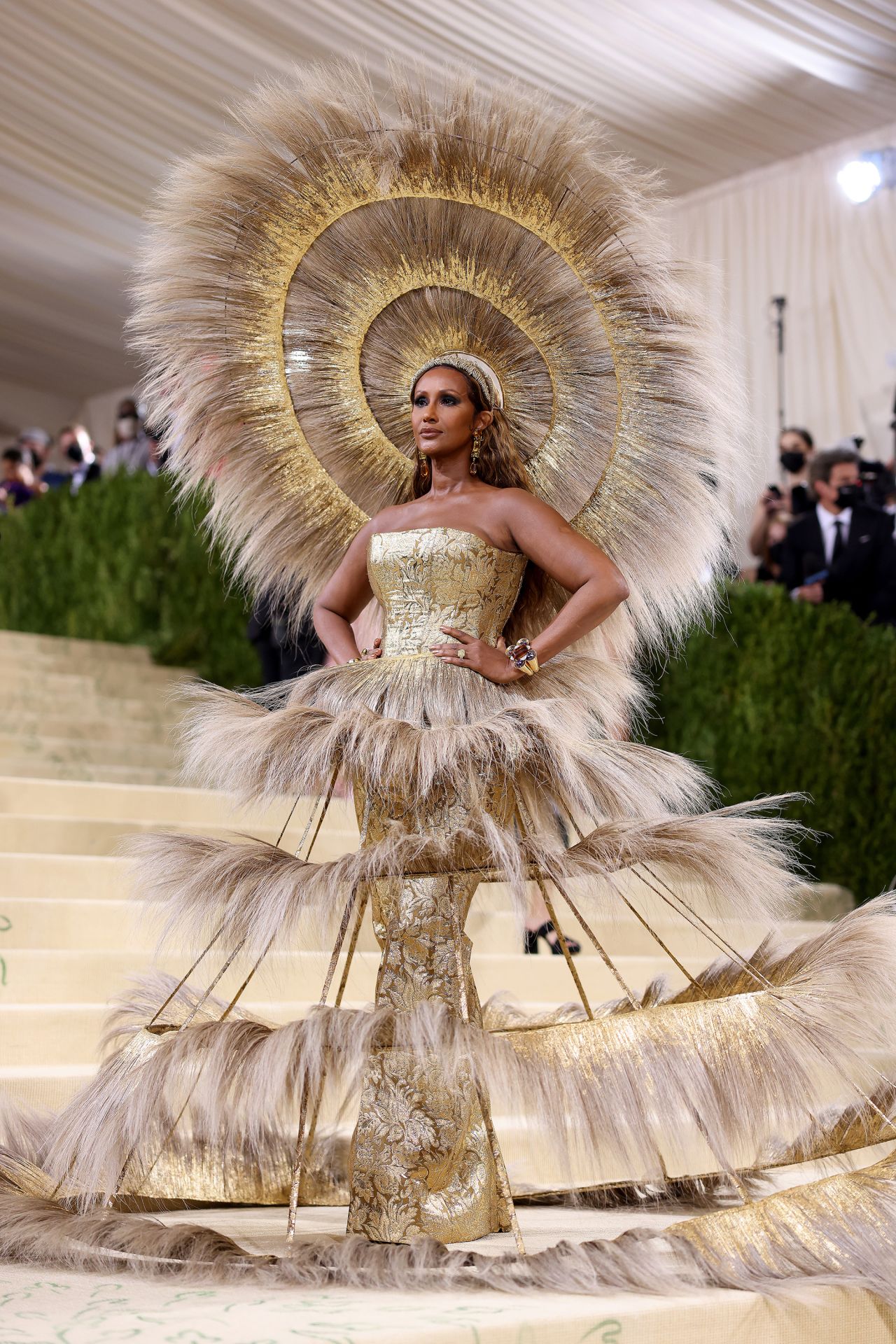 Supermodel Iman turned heads in a dramatic feathery headdress from Harris Reed with a matching tiered skirt over a glittering gold bell-bottom bodysuit.