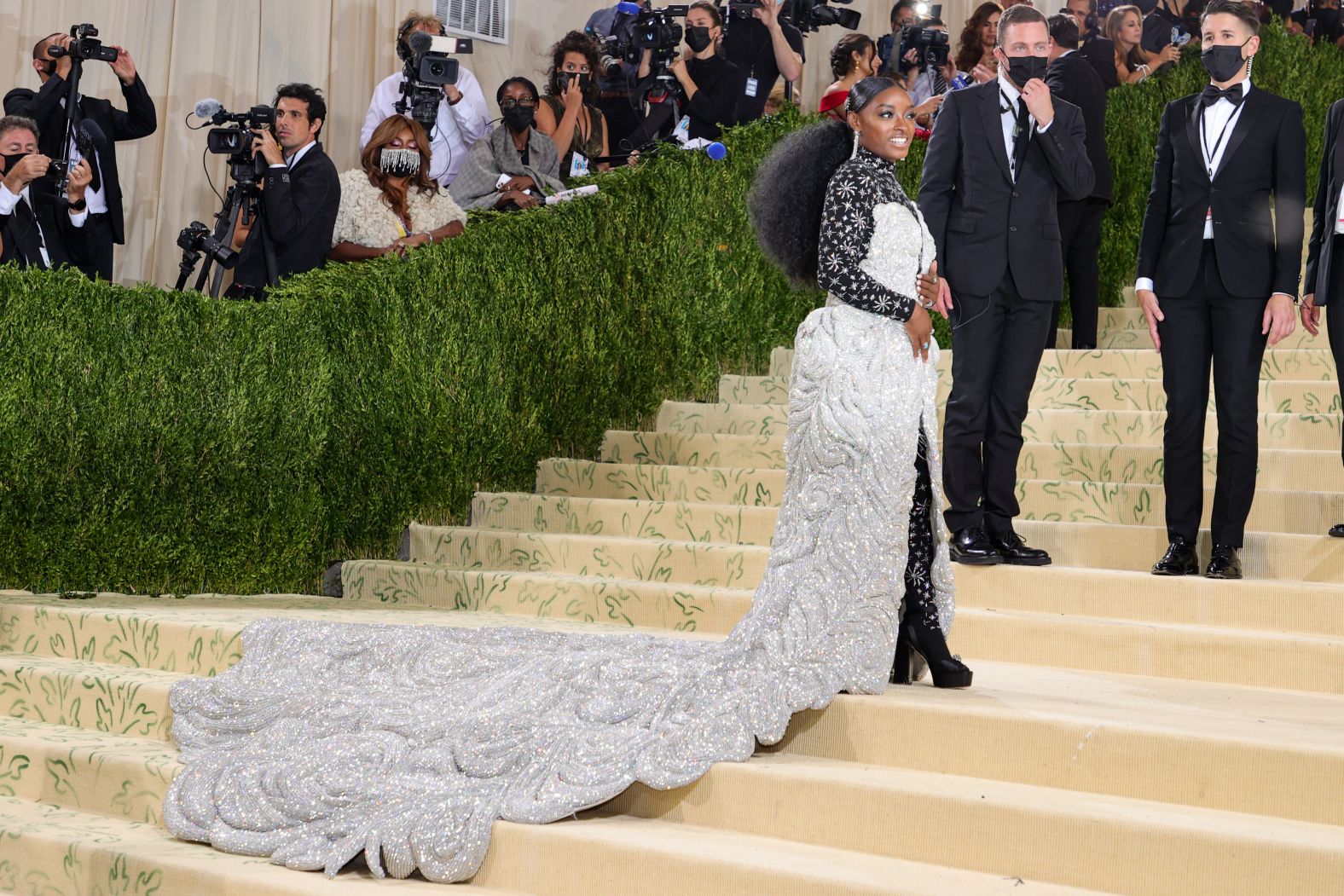 Simone Biles wore a show-stopping gown made by Area in collaboration with Athleta. Her Swarovski-embellished skirt weighed 88 pounds, according to Vogue, and required six people to assist her up the steps. On Instagram, she revealed that the skirt was detachable and hid a fringed cocktail dress -- which she then removed to unveil her final look: a black starry bodysuit.