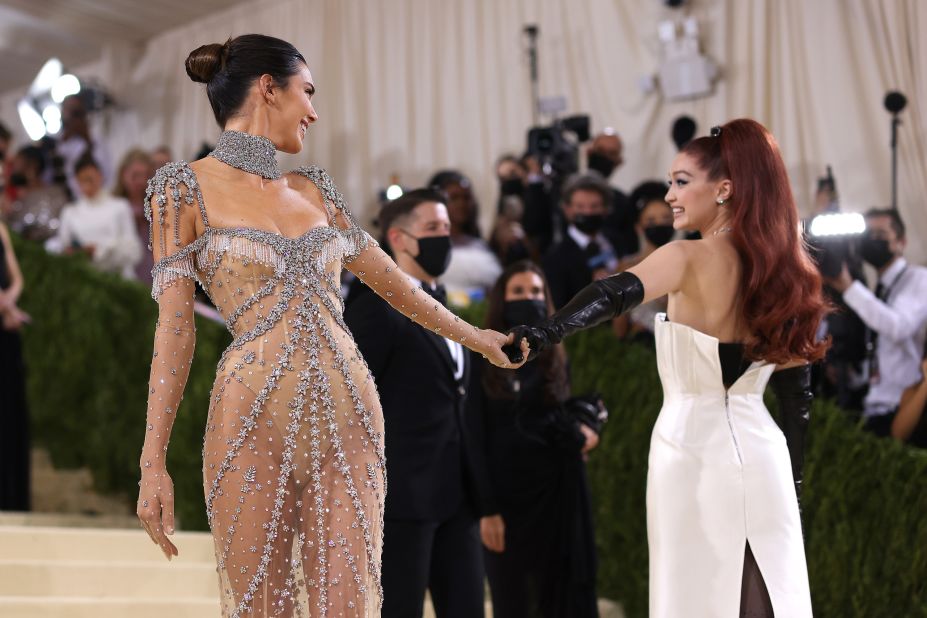 Friends Kendall Jenner and model Gigi Hadid held hands on the red carpet. Wearing her red hair in a high ponytail, the latter channeled the spirit of old Hollywood in a classic corseted white sheath dress by Prada and black evening gloves.