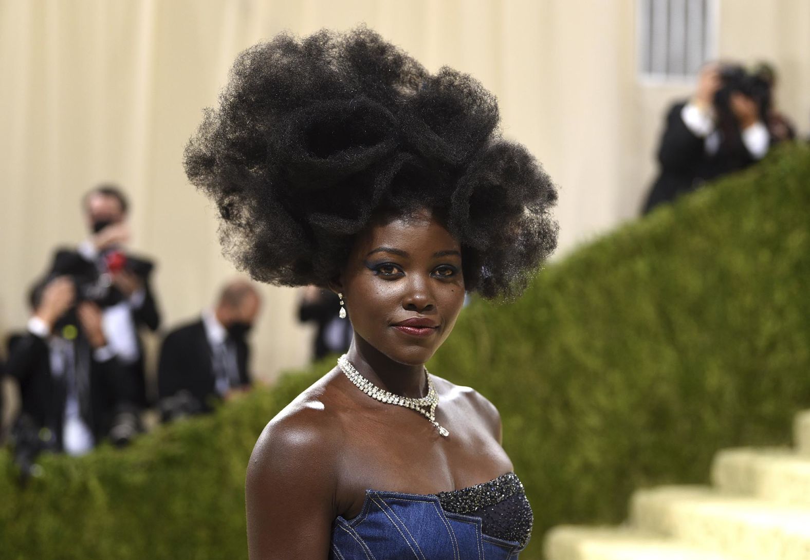 Lupita Nyong'o arrived wearing a denim gown by Versace, paired with navy blue eyeshadow and big jewels.