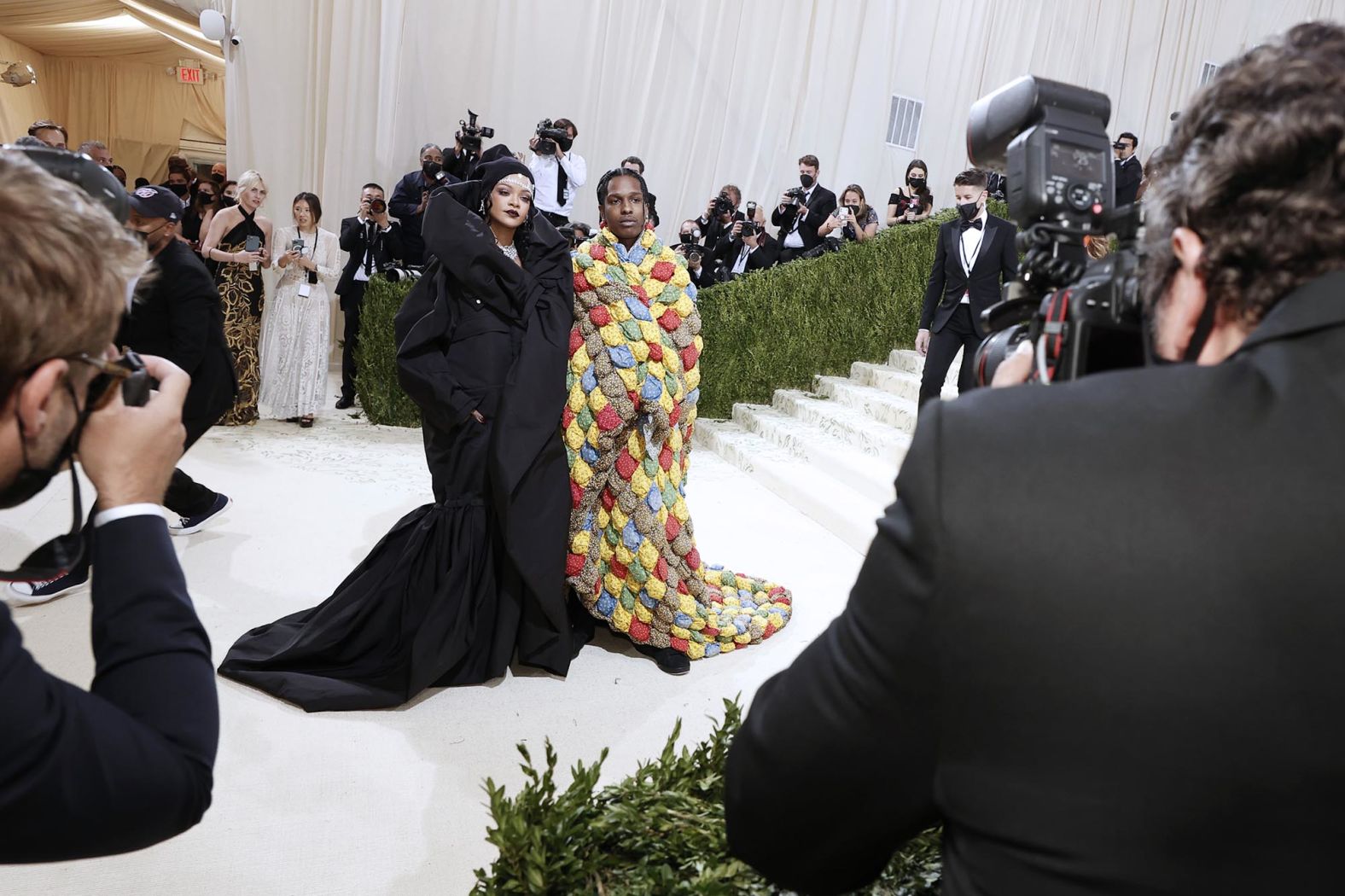 Singer Rihanna and A$AP Rocky swooped in at the very last minute, closing out the Met Gala red carpet in a pair of bold looks. Rihanna wore a voluminous Balenciaga couture coat dress, accessorized with a beanie and diamond forehead accessory. A$AP Rocky meanwhile wore a colorful quilted creation by ERL.