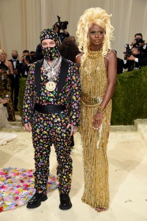 J Balvin and "RuPaul's Drag Race" winner Symone both arrived wearing Moschino. Balvin wore a suit and matching balaclava covered in florals, alongside a stack of necklaces. In contrast, Symone chose a fringed golden dress which trailed all the way to the floor. <a href="index.php?page=&url=https%3A%2F%2Fwww.cnn.com%2Finteractive%2F2021%2F09%2Fstyle%2Fsymone-met-gala-cnnphotos%2F" target="_blank">Related: Getting Met Gala-ready with 'Drag Race' star Symone</a>