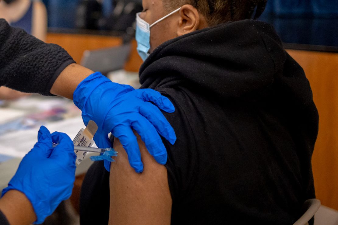 A health care worker vaccinates a teen at West Philadelphia High School in Philadelphia. 