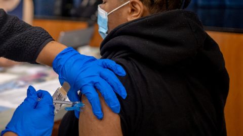 A health care worker vaccinates a teen at West Philadelphia High School in Philadelphia. 