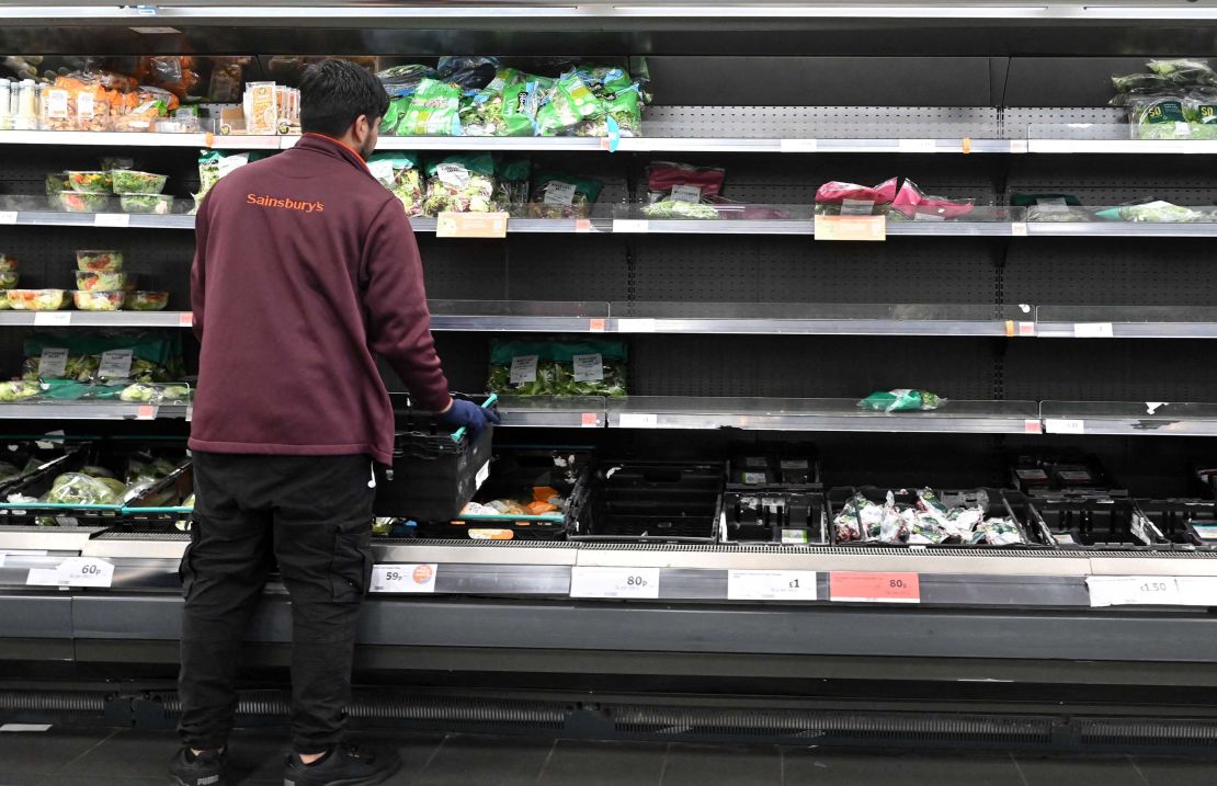 A worker restocks empty shelves of lettuce and salad leaves inside a Sainsbury's supermarket in London on September 7, 2021. 