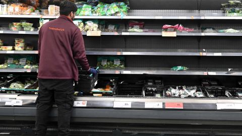A worker restocks empty shelves of lettuce and salad leaves at a Sainsbury's supermarket in London on September 7, 2021. 