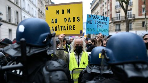 A protester holds signs reading, "No to the health pass" and "Vaccine: keep away from our children," at a demonstration in the western Paris suburb of Neuilly-sur-Seine on August 7.