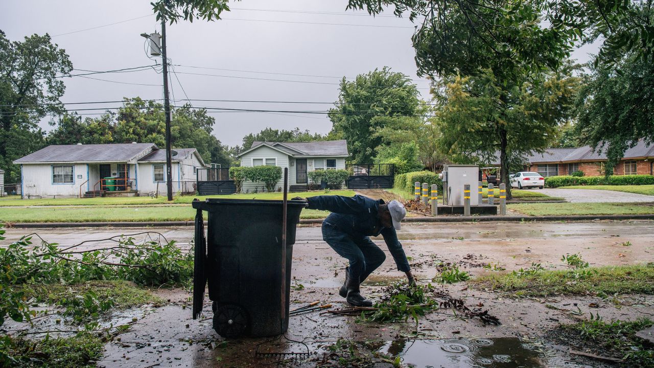 Dallas Baines of Houston throws fallen tree branches into the trash.