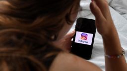 In this photo illustration, a person looks at a smart phone with a Instagram logo displayed on the screen, on August 17, 2021, in Arlington, Virginia. (Photo by OLIVIER DOULIERY / AFP) (Photo by OLIVIER DOULIERY/AFP via Getty Images)