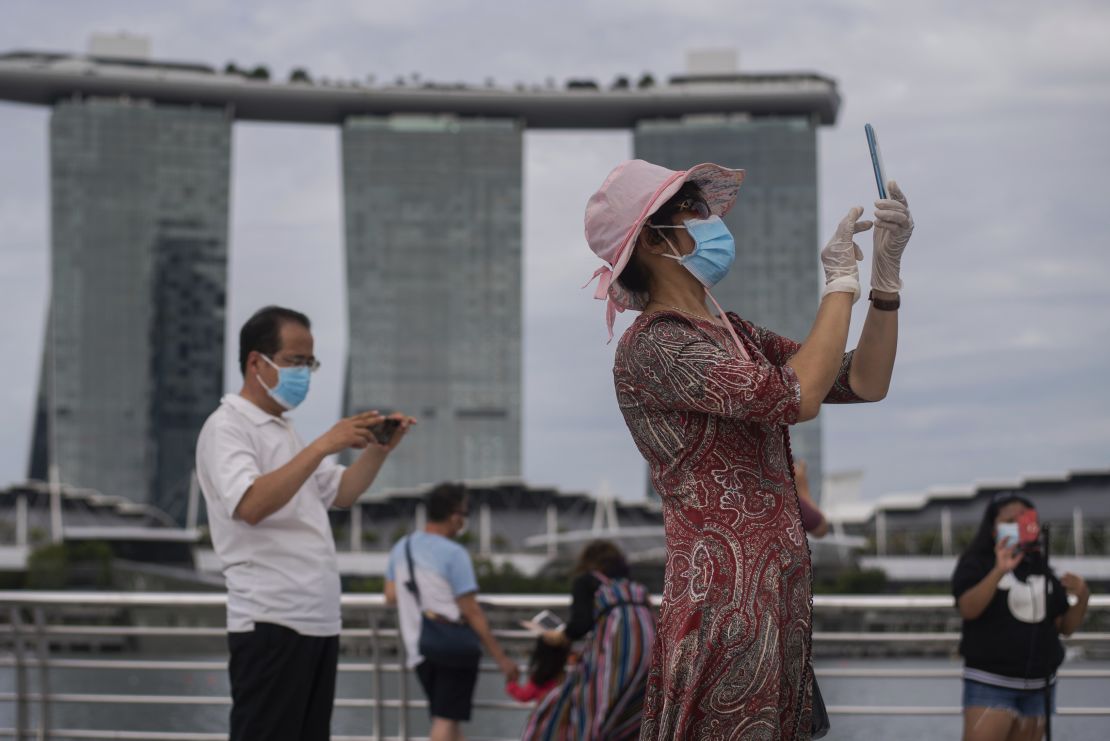 A woman wearing mask and gloves takes pictures at Singapore's Marina Bay on August 1, 2021.