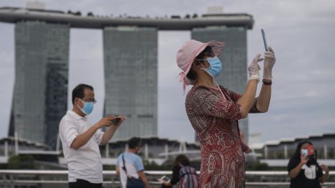 A woman wearing mask and gloves takes pictures at Singapore's Marina Bay on August 1, 2021.