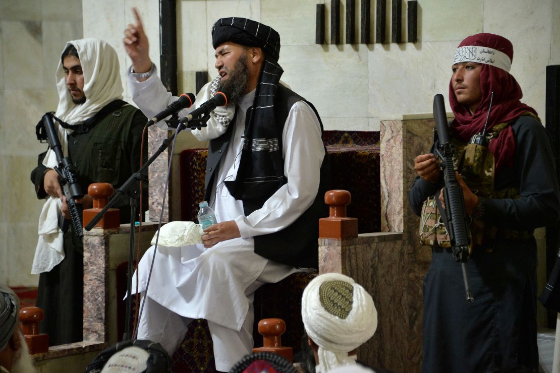 Armed Taliban fighters stand next to a Mullah, a religious leader, speaking during Friday prayers at the Pul-e Khishti Mosque in Kabul on September 3.