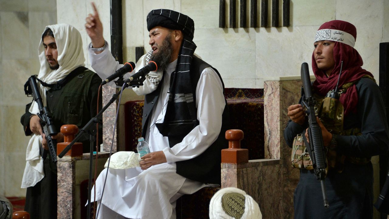 Armed Taliban fighters stand next to a Mullah, a religious leader, speaking during Friday prayers at the Pul-e Khishti Mosque in Kabul on September 3.