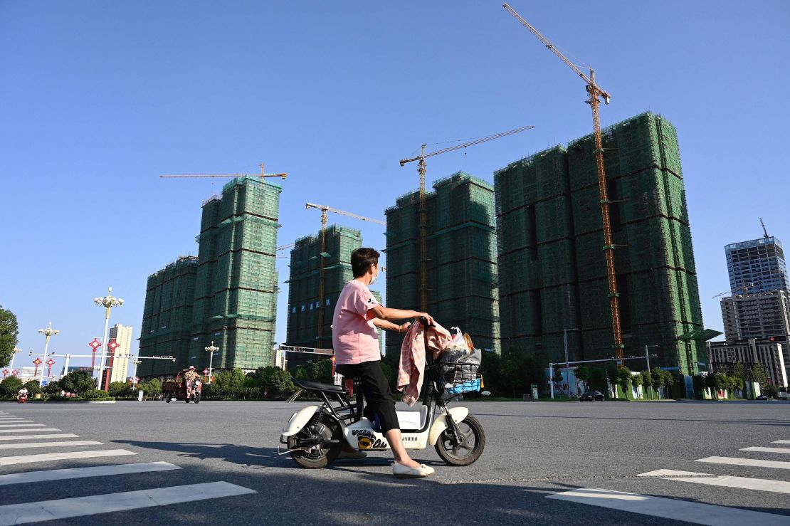 A woman riding a scooter past the construction site of an Evergrande housing complex in Zhumadian, Henan province on Sept. 14, 2021. 