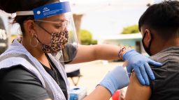 A 17-year-old receives a first dose of the Pfizer Covid-19 vaccine at a mobile vaccination clinic during a back to school event offering school supplies, Covid-19 vaccinations, face masks, and other resources for children and their families at the Weingart East Los Angeles YMCA in Los Angeles,