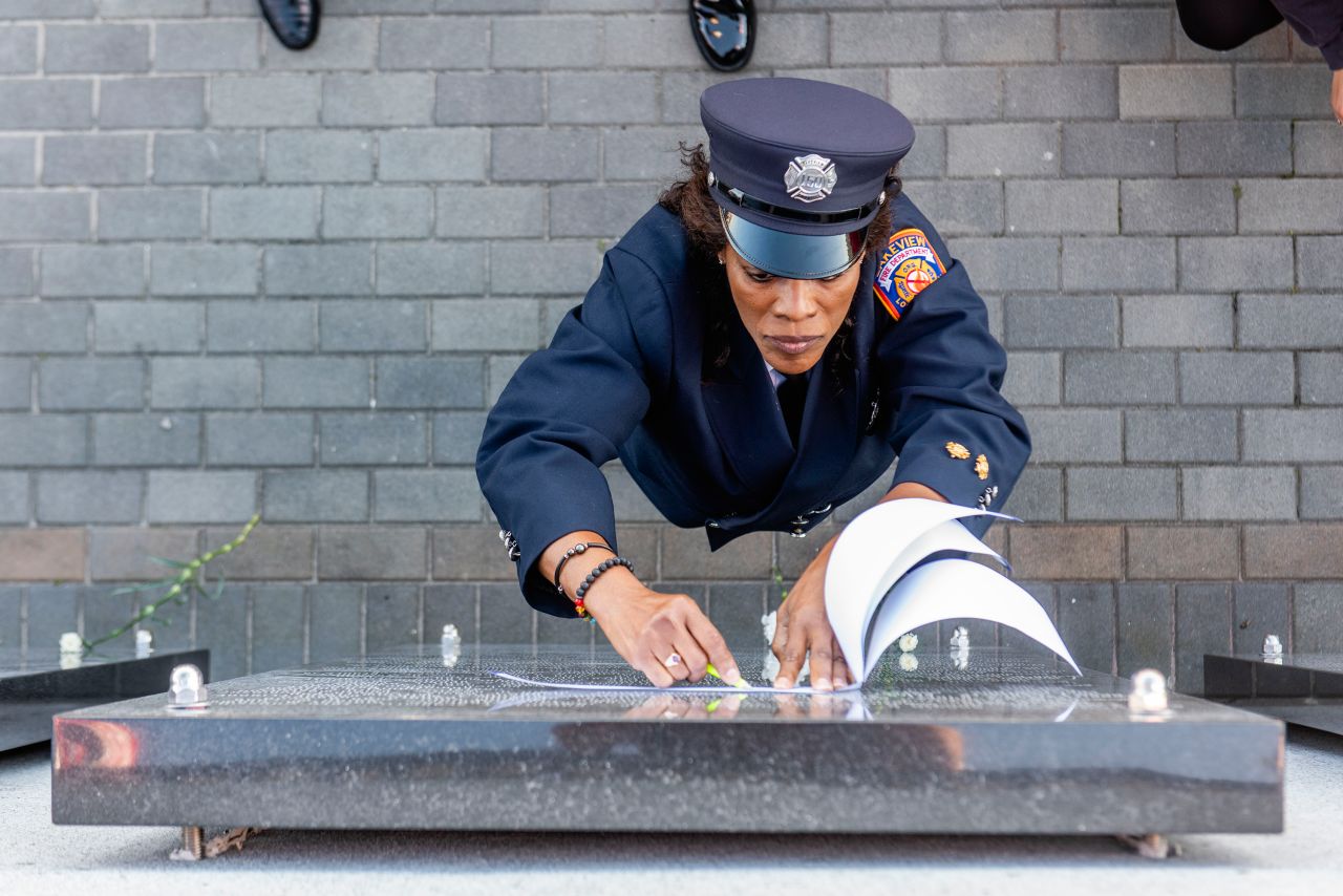 Renee Farrell of the Lakeview Fire Department traces over the name of her late husband at a 9/11 memorial in Lido Beach, New York, on Saturday, September 11.