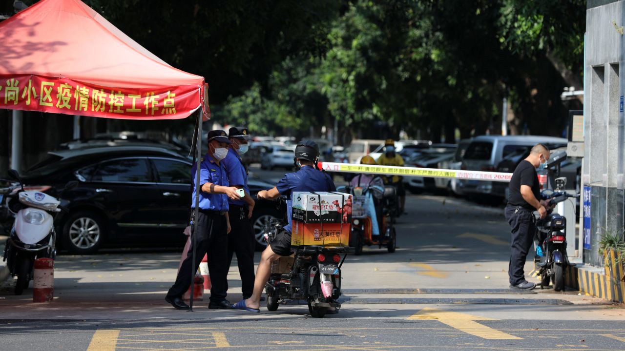Government workers stop a biker at the entrance to a residential block under lockdown in Xiamen in southeast China's Fujian province on September 14.