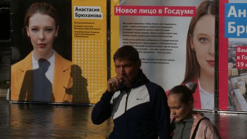 People walk past posters of Anastasia Bryukhanova, an independent candidate for the State Duma poll, on September 5.