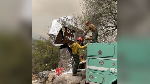 Firefighters assigned to the KNP Complex Fire prepare the historic Sequoia entrance sign for the possibility of fire in the area by wrapping it with aluminum-based burn-resistant material.