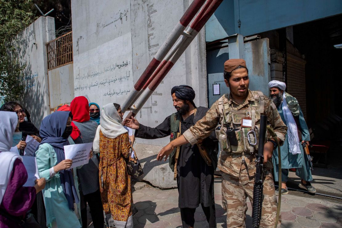 Afghan women converse with a Taliban fighter while they hold placards during a demonstration demanding better rights for women in front of the former Ministry of Women Affairs in Kabul on September 19.