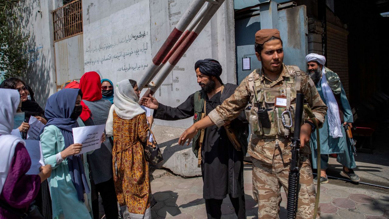 Afghan women converse with a Taliban fighter while they hold placards during a demonstration demanding better rights for women in front of the former Ministry of Women Affairs in Kabul on September 19.