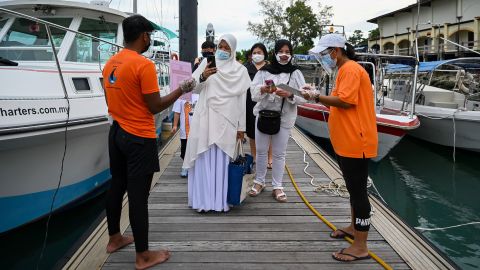 Passengers scan the MySejahtera app, used to monitor the Covid-19 coronavirus status, before boarding a catamaran yacht in Langkawi on September 17, 2021, as the holiday island reopened to domestic tourists following closures due to Covid-19 restrictions. (Photo by Mohd RASFAN / AFP) (Photo by MOHD RASFAN/AFP via Getty Images)
