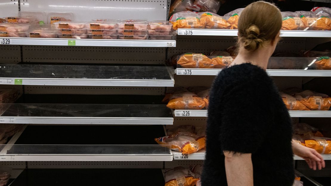A woman walks past empty shelves that stock chicken at an Asda supermarket on September 19, 2021, in London.