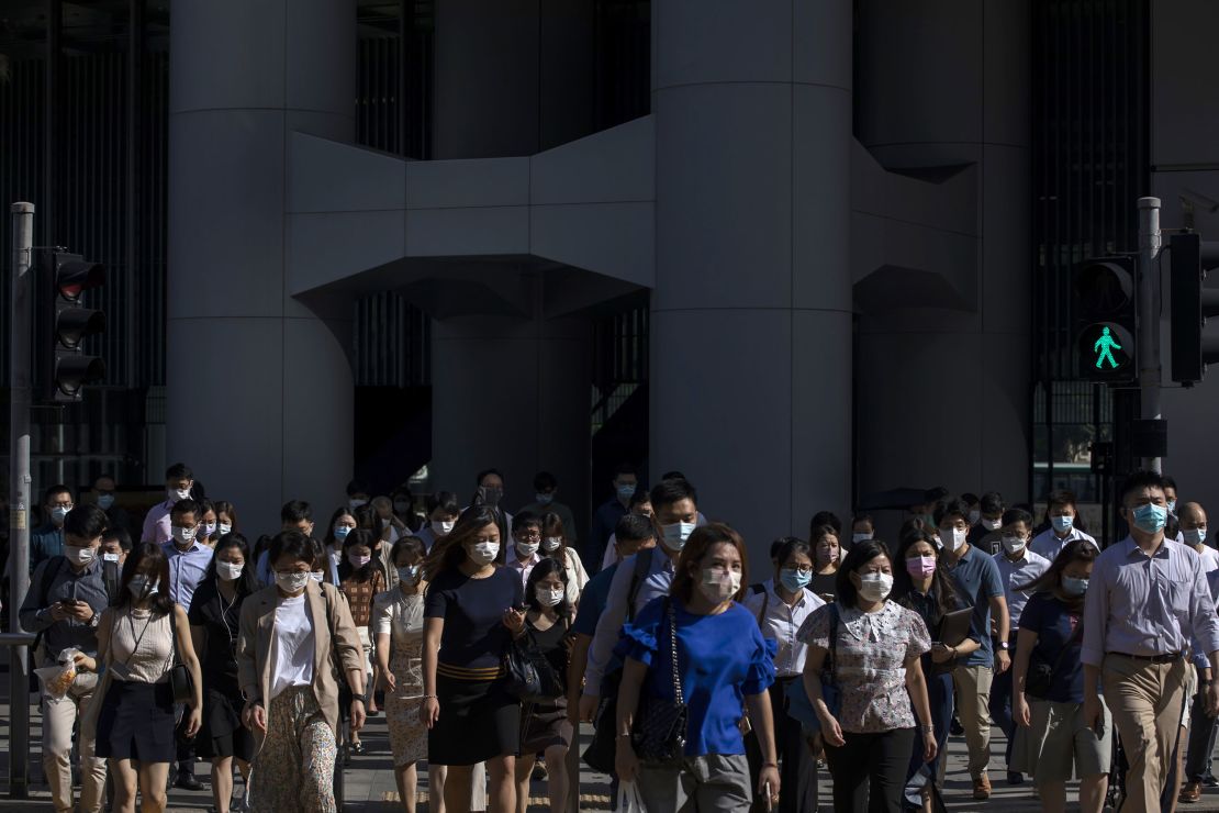 Morning commuters wearing protective masks cross a road in Central, Hong Kong on Aug. 18.