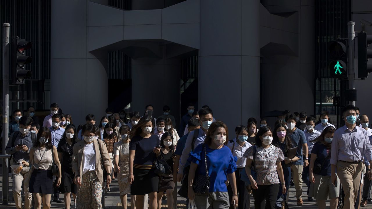 Morning commuters wearing protective masks cross a road in Central, Hong Kong on Aug. 18.