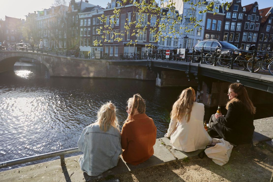 Some folks sit in the sun on a canal in Amsterdam. The Dutch treasure their niksen — or do nothing time.