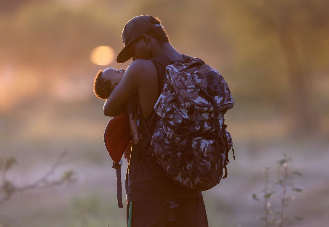 An exhausted Haitian father cradles his son on the Mexican side of the Rio Grande from Del Rio, Texas, on September 19, 2021, in Ciudad Acuna, Mexico. 