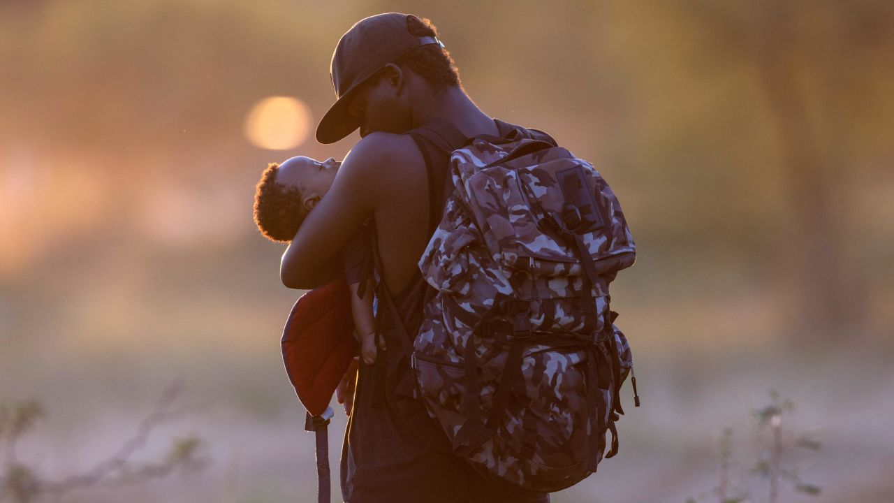 An exhausted Haitian father cradles his son on the Mexican side of the Rio Grande from Del Rio, Texas, on September 19, 2021, in Ciudad Acuna, Mexico.
